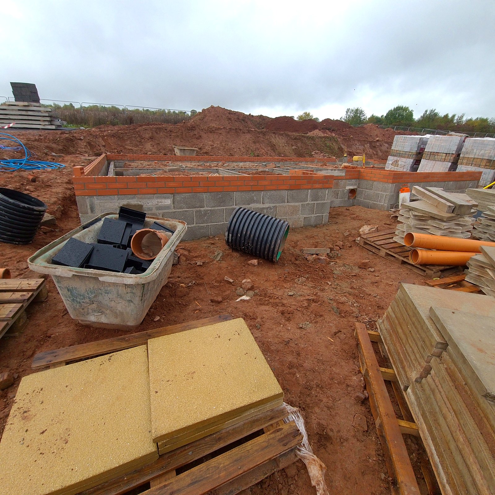 Substructure blockwork and brickwork with drainage pipework and below-ground services during foundation-stage construction