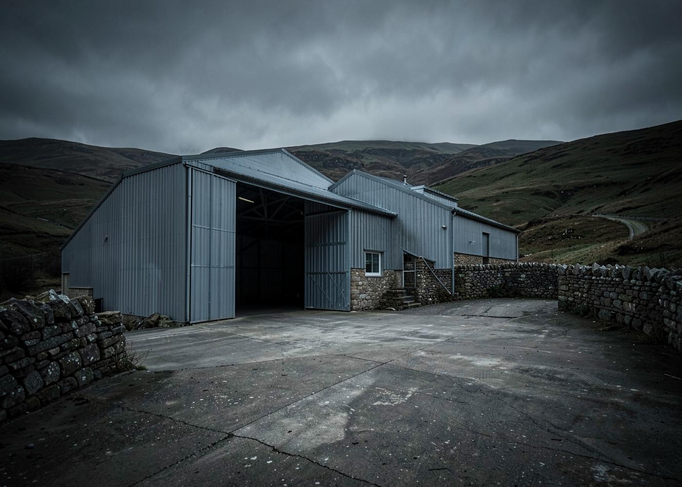 Steel-portal agricultural building and concrete yard on a Cumbrian hill farm